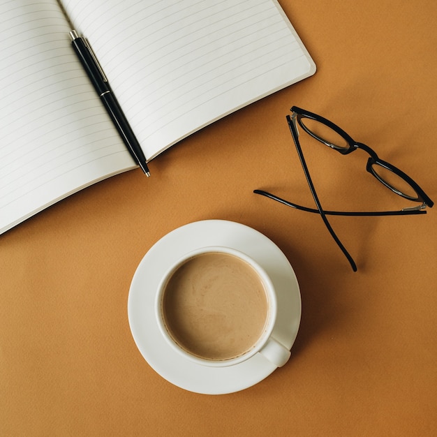 Espacio de trabajo de escritorio de oficina en casa moderno con cuaderno, taza de café, vasos de jengibre