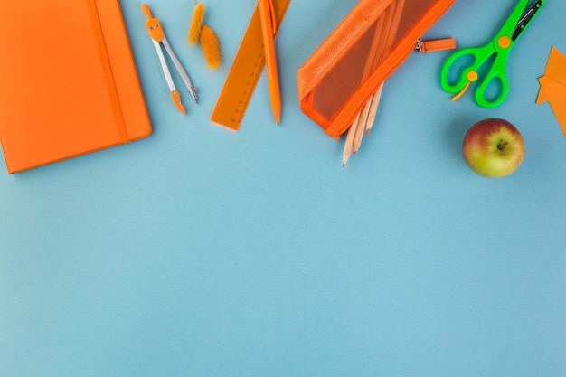 Espacio de trabajo de la escuela u oficina minimalista de moda creativa con suministros de color naranja sobre fondo azul ...