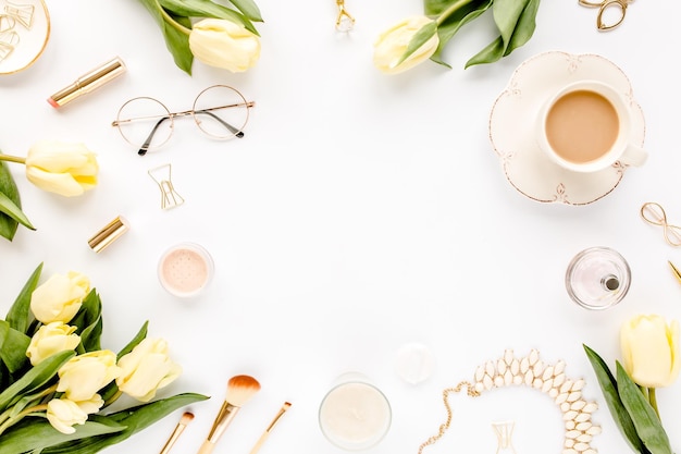 Espacio de trabajo femenino con flores de tulipán amarillo moda femenina accesorios dorados gafas de diario en blanco