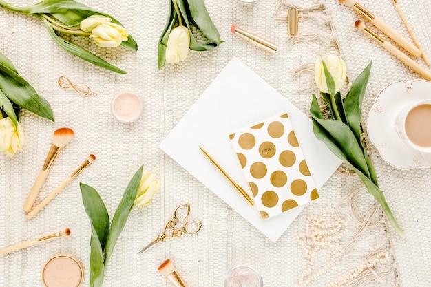 Foto espacio de trabajo femenino con flores de tulipán amarillo moda femenina accesorios dorados gafas de diario en blanco