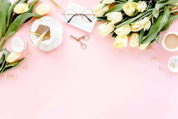 Espacio de trabajo femenino con ramo de flores de tulipán accesorios dorados diario sobre fondo rosa flat lay wom