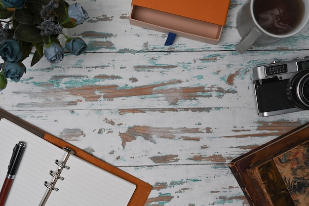 Foto espacio de trabajo de fotógrafo con cuaderno, cámara y taza de café.