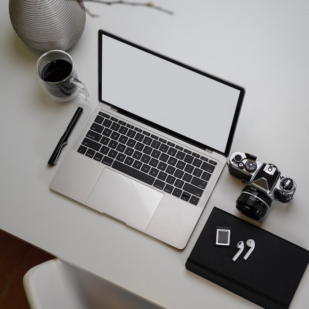 Espacio de trabajo de fotógrafo moderno con maqueta portátil, cámara, agenda y decoración.