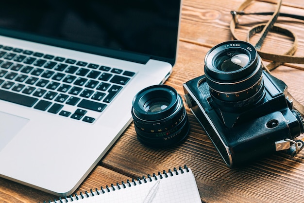 Espacio de trabajo para el fotógrafo Tenga una nota de cámara de película portátil en la mesa de madera