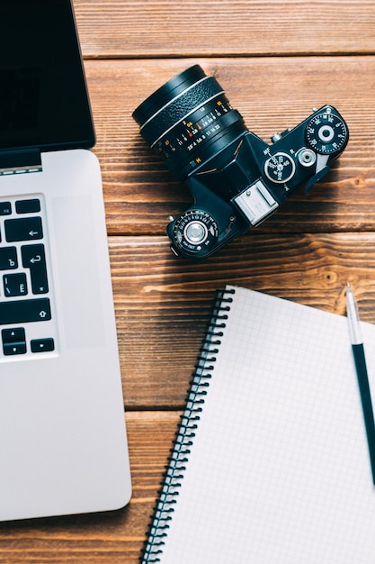 Espacio de trabajo para el fotógrafo Tenga una nota de cámara de película portátil en la mesa de madera