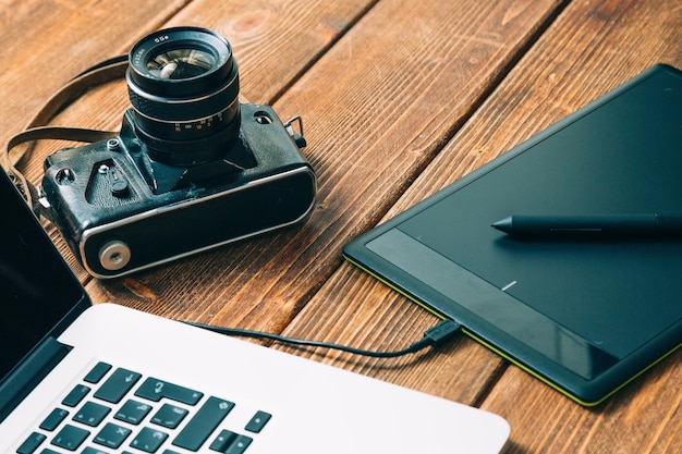 Espacio de trabajo para el fotógrafo Tenga una tableta gráfica de cámara de película portátil en una mesa de madera