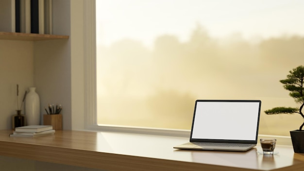 Espacio de trabajo en el hogar con maqueta de computadora portátil en la mesa de madera contra la ventana con vista a la naturaleza