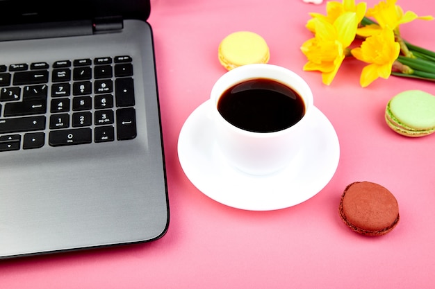 Espacio de trabajo con libreta, café, macarons y flores.