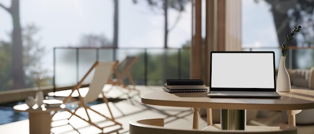 Espacio de trabajo con maqueta de computadora portátil en una mesa de madera en la sala de estar con acceso a la piscina