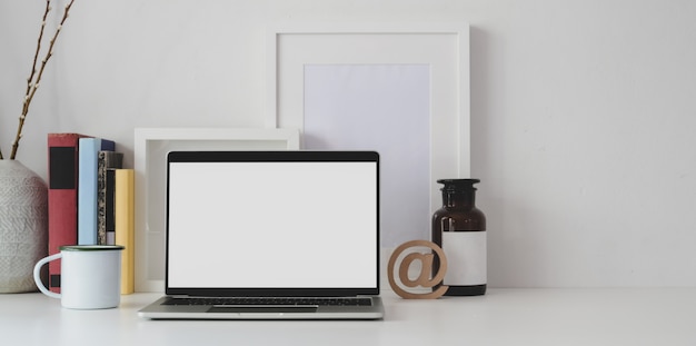 Espacio de trabajo mínimo con computadora portátil de pantalla en blanco abierta con suministros de oficina y espacio de copia