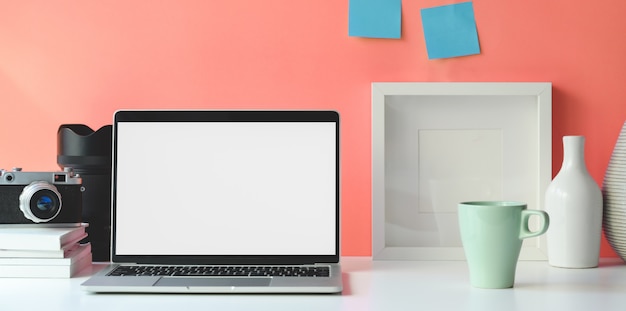 Espacio de trabajo mínimo con computadora portátil con pantalla en blanco abierta