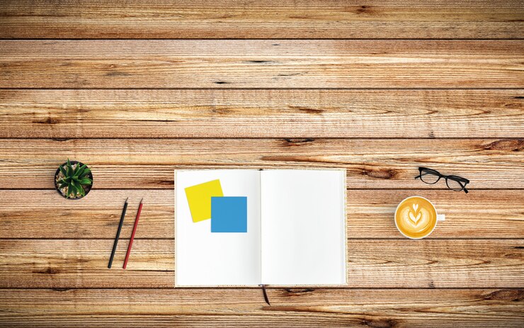 Foto espacio de trabajo moderno con taza de café, papel, cuaderno y lápices sobre madera.