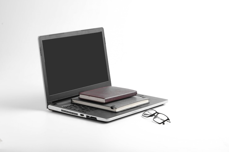 Foto espacio de trabajo moderno con teclado portátil, portátil, gafas en superficie blanca.