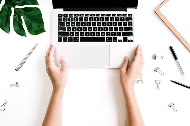 Espacio de trabajo de la oficina en casa con las manos trabajando en el teclado de la computadora portátil