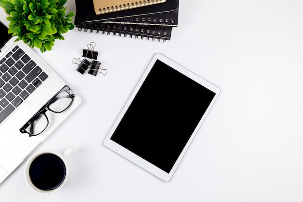 El espacio de trabajo en la oficina con la tableta y con las pantallas en blanco están en la parte superior