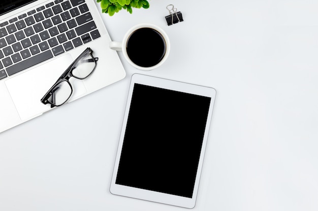 Espacio de trabajo en la oficina con tableta y con pantallas vacías en blanco.