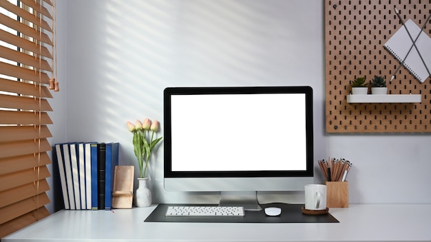 Espacio de trabajo ordenado y ordenado con computadoras, libros y suministros de oficina en la mesa blanca.