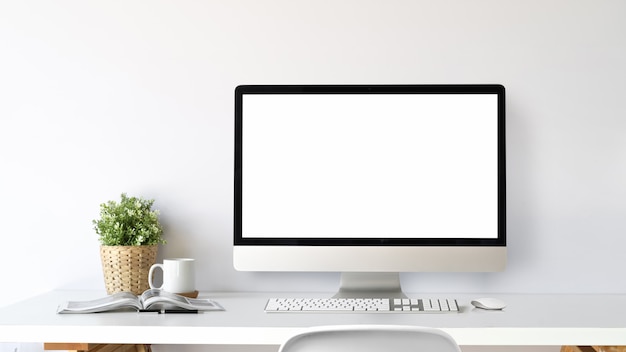 Foto espacio de trabajo con ordenador de pantalla en blanco sobre una mesa blanca