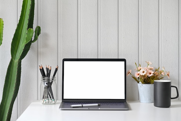 Espacio de trabajo con pantalla portátil en blanco.