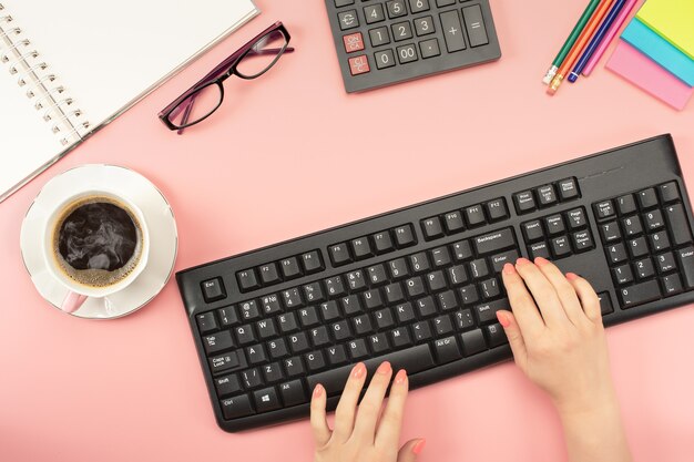 Espacio de trabajo plano. Mujer que trabaja en la pc, taza de café, calculadora, computadora, cuaderno, planificador y papelería con espacio de copia