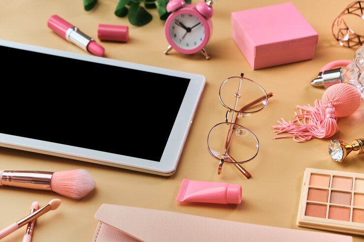 Foto espacio de trabajo con tableta blanca, bloc de notas, gafas, bolígrafos, accesorios de belleza en superficie beige pastel