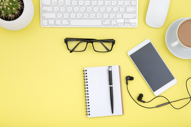 Espacio de trabajo con tableta, teclado, taza de café y anteojos.