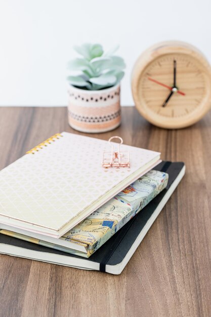 Foto espacio de trabajo temático femenino con cuaderno de anillo rosado y cuaderna de bocetos de cubierta negra en mesa de madera