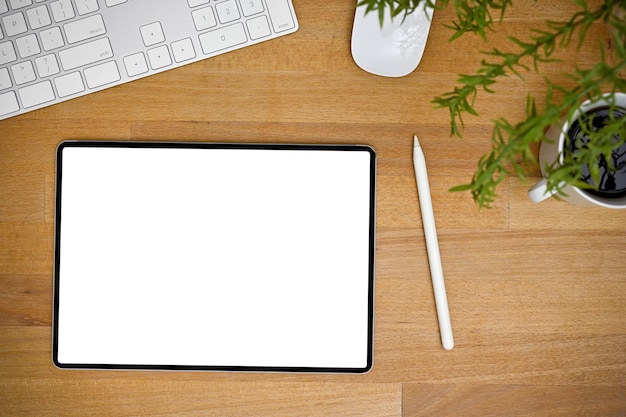 Espacio de trabajo de vista superior con tableta de pantalla en blanco en la mesa de madera