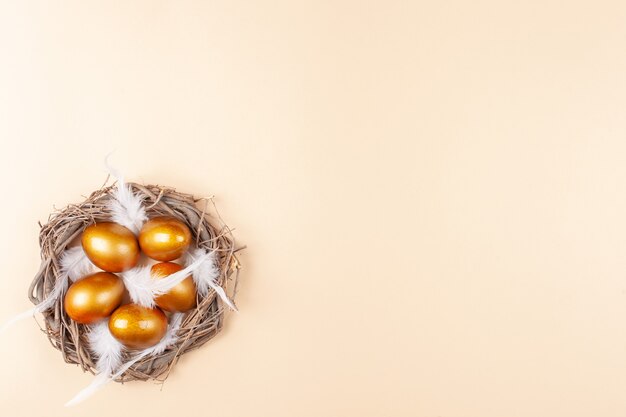 Espacio vacío para texto, una pancarta de feliz Pascua. Huevos dorados pintados, plumas blancas.