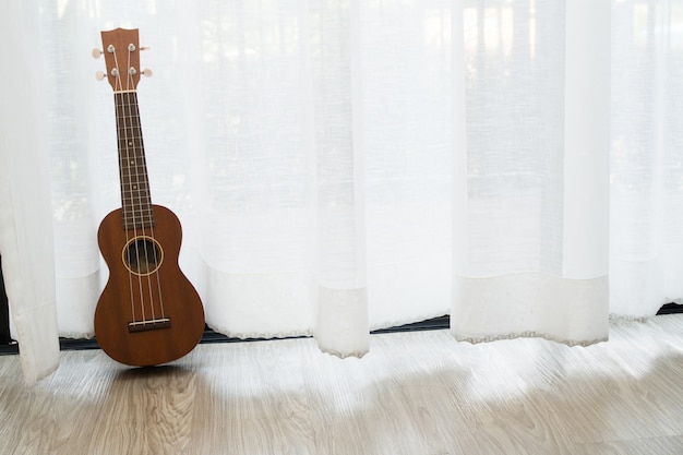 espaço certo cópia com ukulele de madeira na cortina branca