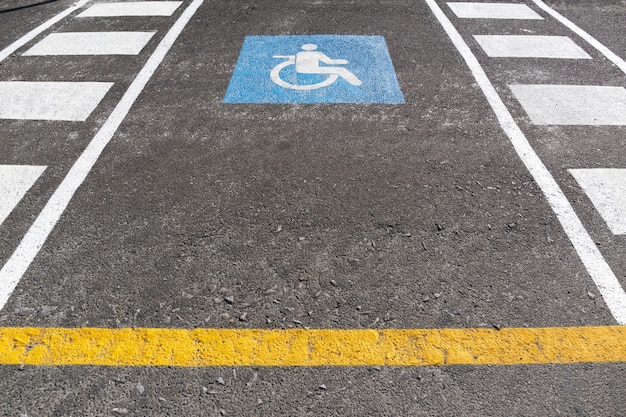 Espaço de estacionamento para cadeiras de rodas no exterior. Símbolo de sinal de trânsito para deficientes físicos pintado no asfalto