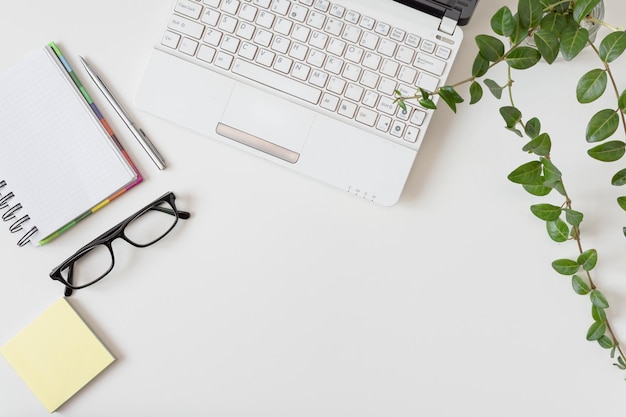 Espaço de trabalho com diário de laptop e outros objetos em fundo branco Mesa de escritório elegante