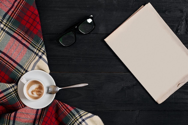 Espaço de trabalho com jornal xícara de café lenço óculos elegante mesa de escritório outono ou inverno conceito plana ...