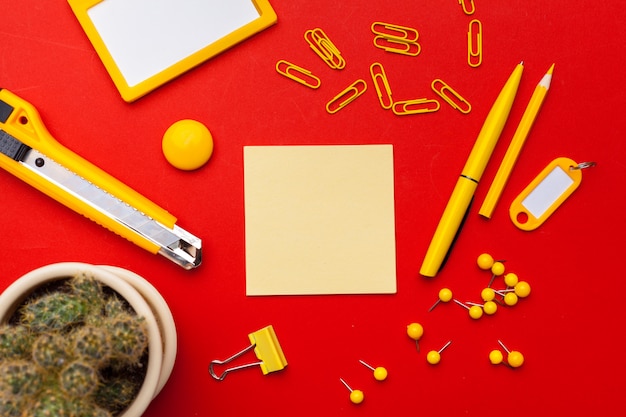 Espaço de trabalho com notas adesivas em branco, material de escritório em vermelho