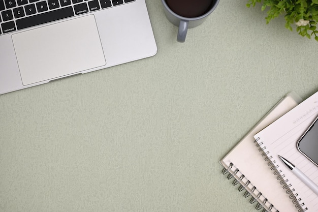 Espaço de trabalho com notebook de caneta de xícara de café para laptop e espaço em fundo verde