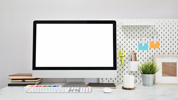 Espaço de trabalho contemporâneo com computador de tela vazia e material de escritório na mesa de mármore.