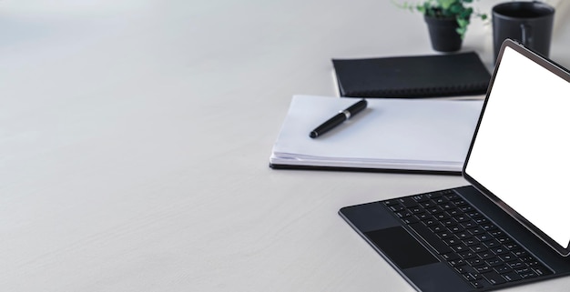 Espaço de trabalho criativo com tablet digital de tela branca e teclado mágico na mesa branca