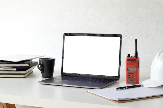 Espaço de trabalho de engenheiro com laptop e capacete de segurança.