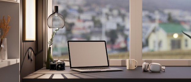 Espaço de trabalho de escritório elegante com fone de ouvido de maquete de laptop e decoração na mesa preta contra a janela