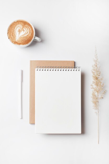 Espaço de trabalho de escritório em casa com caderno, caneta, café e modelo de trabalho de negócios de grama de pampa