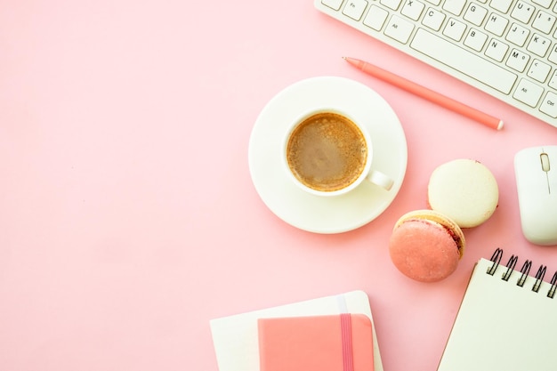 Espaço de trabalho de escritório Mesa de escritório rosa lisa com teclado, notebook e xícara de café