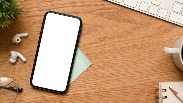 Espaço de trabalho de mesa de escritório de madeira com teclado de fones de ouvido de maquete de telefone celular e material de escritório acima