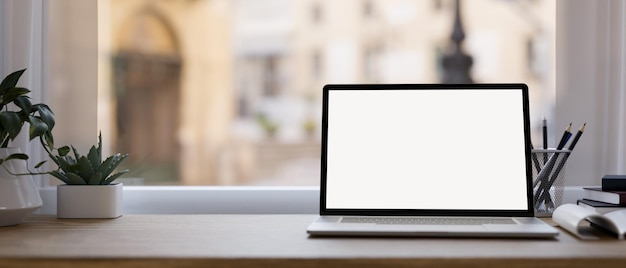 Espaço de trabalho de mesa de escritório moderno com maquete de notebook e espaço na mesa de madeira sobre a janela