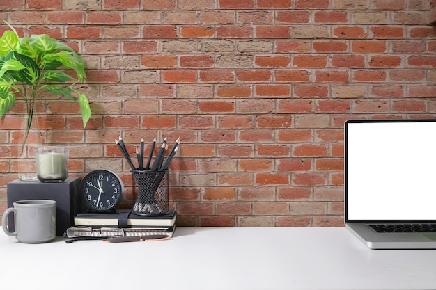 Espaço de trabalho elegante com porta-lápis de xícara de café portátil e planta em vaso na mesa branca Tela em branco e espaço de cópia para texto publicitário