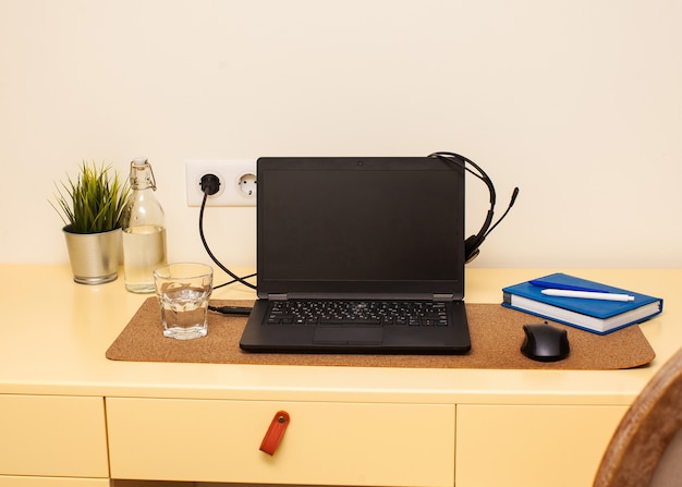 Espaço de trabalho em casa, laptop, fones de ouvido, caderno de trabalho