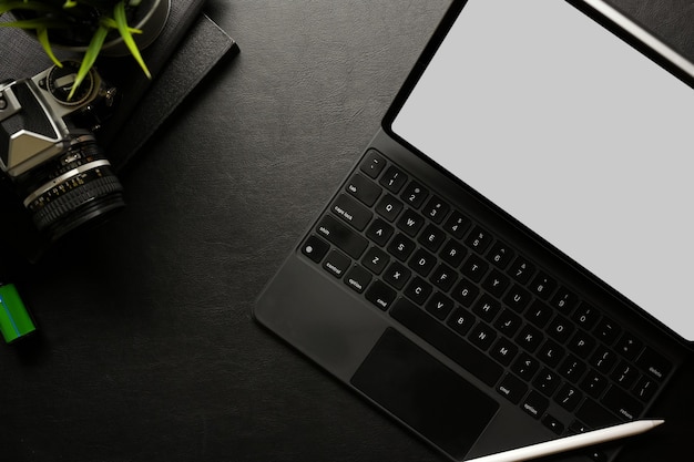 Espaço de trabalho escuro e criativo com acessórios para tablet digital, suprimentos de câmera e vista superior do espaço de cópia
