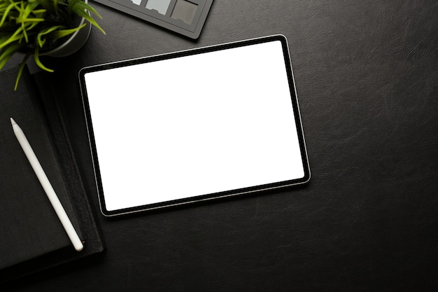 Espaço de trabalho escuro e criativo com tablet digital, incluindo acessórios de tela de recorte e espaço para cópia