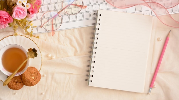 Espaço de trabalho feminino Linda mesa de escritório com teclado de xícara de chá de notebook vazio e vista superior de decoração