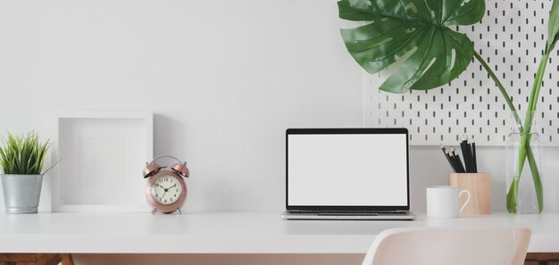 Espaço de trabalho moderno com computador portátil de tela em branco aberta e moldura com decorações