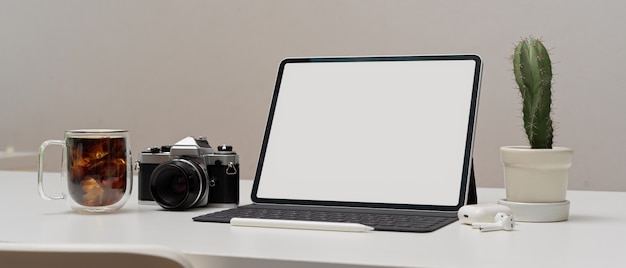 Espaço de trabalho moderno com tablet digital, câmera e xícara de café
